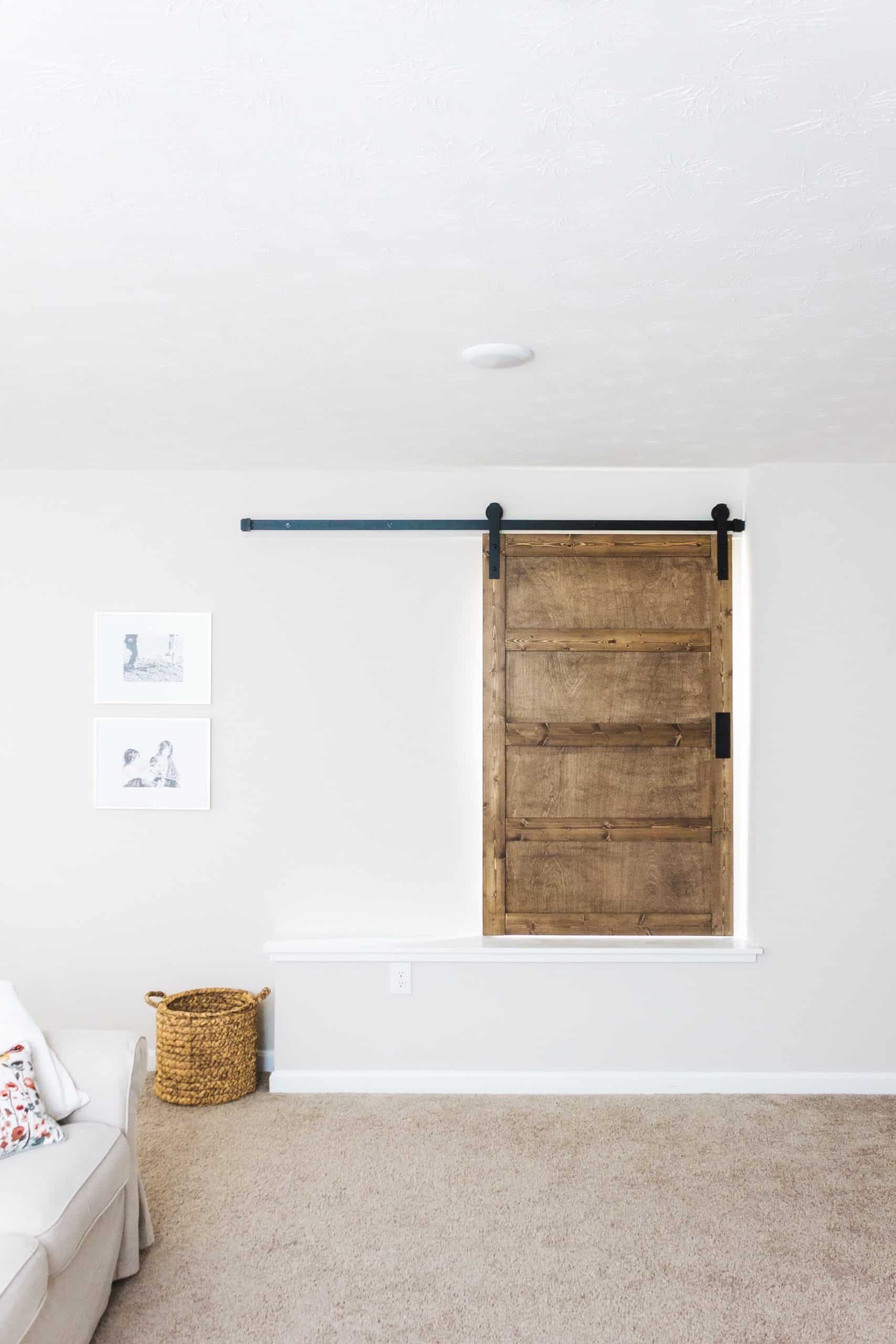 Want to build a modern farmhouse-inspired sliding barn door window covering? Head to www.freeandunfettered.com for the complete tutorial. #diyhome #modernfarmhouse #slidingbarndoor #diyhomedecor 