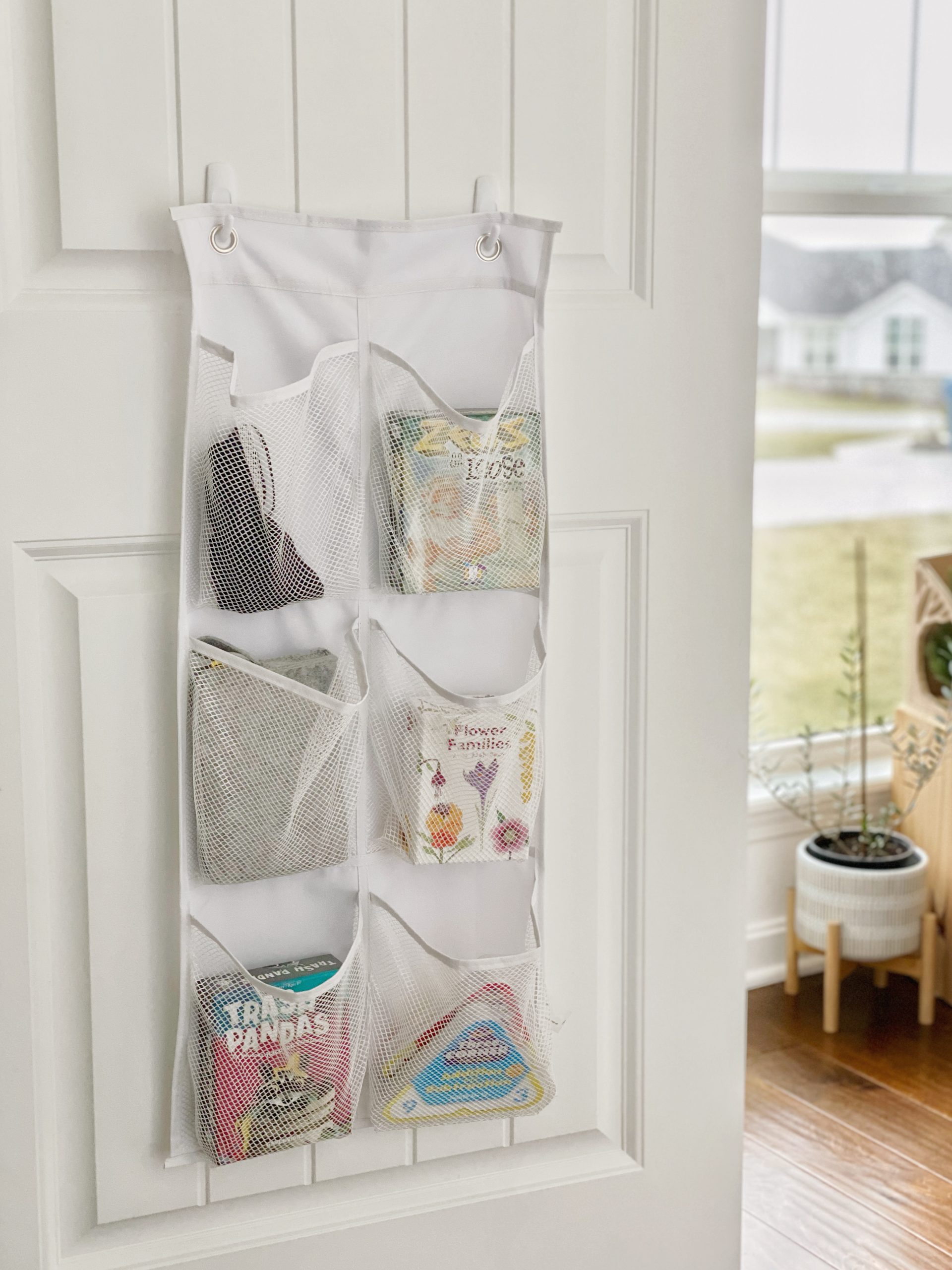 A collection of card games are neatly organized in a hanging pocket organizer that hangs on the back side of the closet door. 